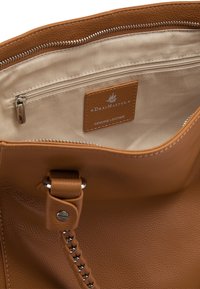 Interno di una borsa in pelle color tan, con una tasca con zip e foderato in beige. Include un'etichetta in pelle con la scritta "DreiMaster Genuine Leather."
