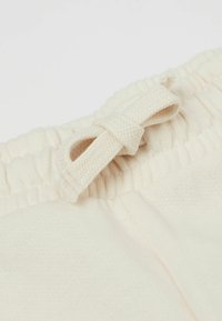 Helle beigefarbene Baumwollshorts mit einem elastischen Bund und einem dekorativen geflochtenen Bindeband. Weiche Textur mit einer einfachen, glatten Oberfläche.