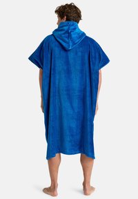 Blå hætteponcho lavet af blødt terry-stof, med korte ærmer og en afslappet pasform, der falder til knæene med en glat tekstur.