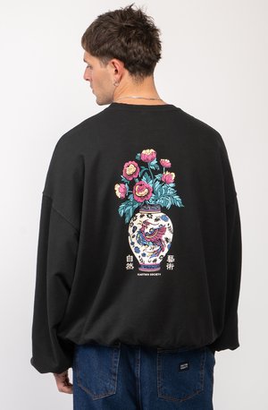 Sweatshirt noir à coupe oversize, présentant un design coloré de fleurs et de vase au dos. Matière en coton, col côtelé et style décontracté.