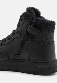 Czarne wysokie botki wykonane z ekoskóry, z miękkim futrzanym wykończeniem, z bocznym zamkiem błyskawicznym, teksturowanymi akcentami i gumową podeszwą.