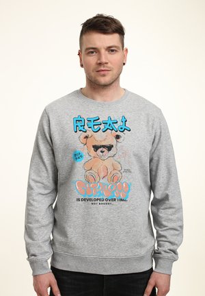 Grå sweatshirt med grafik af en tegneserie-bjørn med solbriller, blå tekst og fed skrift. Materialet er blødt med ribbede manchetter.