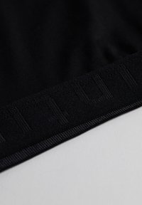 Svart textil med en slät, matt yta och ett kontrasterande, texturerat band som har ett subtilt mönster och präglad text längs kanten.