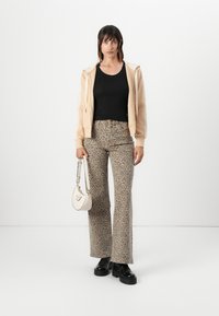 Bežna zip-up kapuca preko črne majice, v kombinaciji z leopardjastimi flare hlačami. Dodatki vključujejo majhno belo torbico. Črne platform škornje.