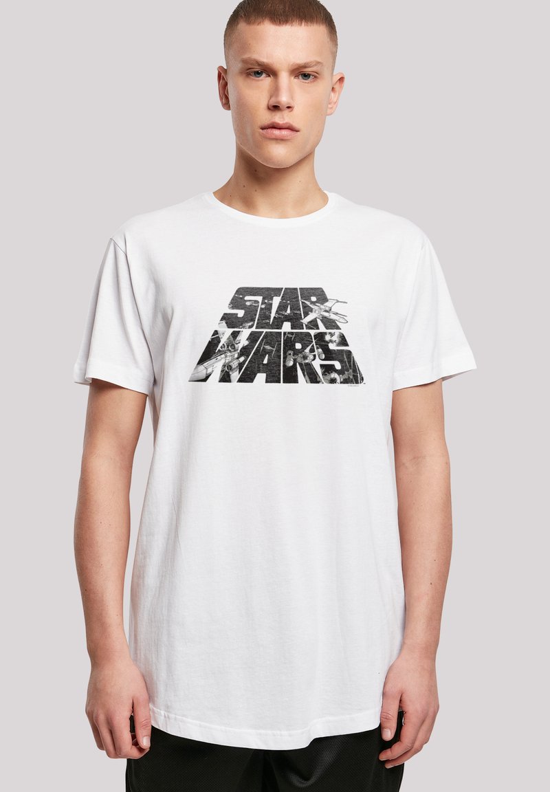 Hvit bomull T-skjorte med svart grafisk trykk av "STAR WARS" med romtema. Rund hals og korte ermer.
