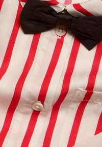 Röd och vit randig skjorta med svart fluga och knappstängning, gjord av ett slätt tyg med en enda bröstficka.