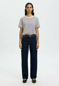 Stripet t-skjorte i hvit og marineblå, kombinert med mørkeblå høyt belte vide jeans og et brunt belte, fullført med brune flate sko.