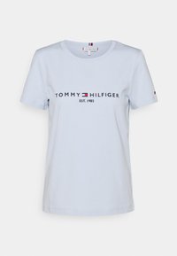 Vaalea sininen puuvillapaita, jossa on pyöreä kaula-aukko ja lyhyet hihat. Rintamuksessa tummalla printillä "TOMMY HILFIGER" -logo ja "EST. 1985".