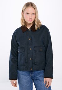 Mörkblå jacka med krage i brunt cordtyg, prydd med guldmetallknappar och två framfickor, designad med en avslappnad passform.