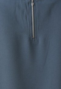 Dark blue skirt with a textured fabric, featuring a silver zipper on the side. Design emphasizes simplicity and functionality.