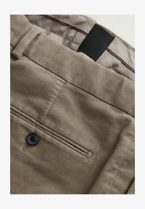 Beige bukser med knaplukning, tekstureret materiale, en forlommes med tonal syning og et kontrasterende indvendigt foringsmønster.