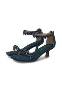 Tacones de gamuza color teal con punta cuadrada, adornados con cristales de color azul y un tacón bajo y transparente. Correa ajustable en el tobillo para un mejor ajuste.