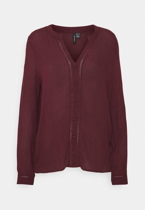 Donker bordeauxrode blouse met lange mouwen, ronde hals, V-vormig knoopsluiting en subtiele stikseldetails aan de voorkant en manchetten.