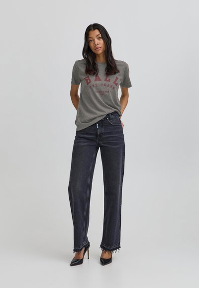 Grå bomulds t-shirt med rød print, parret med vide mørke denim jeans med frynset kant. Sorte spidsede hæle fuldender outfittet.