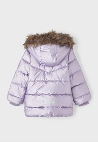 Kurtka puchowa w jasnym lawendowym kolorze z kapturem wykończonym sztucznym futrem, pikowanym wzorem i ściągaczami na mankietach. Stylowy srebrny akcent z tyłu.