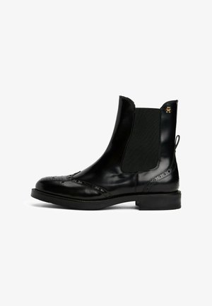 Des bottines Chelsea en cuir noir présentent une finition brillante, des panneaux latéraux élastiques, des détails en brogue sur le bout et une semelle en caoutchouc noir.
