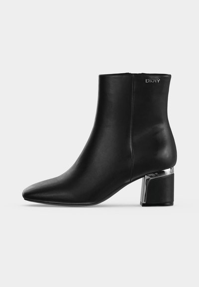 Bottine en cuir noir avec bout pointu, talon bloc avec détail argenté et logo DKNY près du haut sur le côté.
