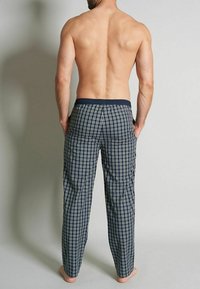 Pantalon de pyjama en motif à carreaux navy avec taille élastique, doté d'une coupe décontractée et de deux poches arrière. Le tissu semble léger et doux.