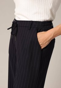 Marine gestreepte op maat gemaakte broek met een drawstring taille en zijzakken. De stof heeft een soepele textuur met contrasterende lichte streepjes.