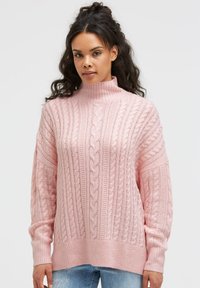 Gestrickter rosa Rollkragenpullover mit Zopfmuster, gerippten Bündchen und Saum. Das Design zeichnet sich durch eine lockere Passform und strukturierten Stoff aus.