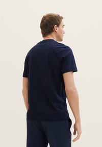Navyblaue Baumwoll-T-Shirt mit kurzen Ärmeln, rundem Ausschnitt und geradem Schnitt; von hinten betrachtet, minimalistisch gestaltet und ohne Grafiken.