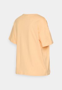 T-shirt de manga curta, de corte solto, em algodão pêssego claro com decote redondo e sem logótipos ou padrões visíveis.
