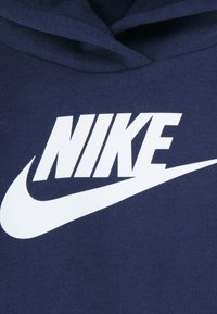 Hanorac albastru marin din material moale, cu un logo alb Nike proeminent și design swoosh centrat în față.