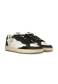 Sneaker basse con una combinazione di pelle crema e suede marrone scuro. Lacci e dettagli neri, suola piatta in gomma e logo sulla lingua.