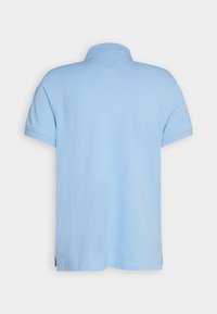 Polo bleu clair à manches courtes vu de dos avec un col côtelé et des fentes latérales à l'ourlet.