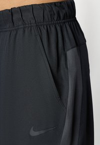 Calções desportivos pretos com uma cintura elástica, bolso lateral e detalhes refletivos. Logótipo da Nike numa tonalidade mais escura na parte da frente.