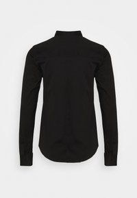 Svart långärmad skjorta med rak krage, knappmanchetter och en slät, matt yta. Har en rundad nederkant och inga synliga dekorationer.