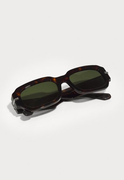 Tortoiseshell sunglasses with dark green lenses, square frames, and a textured accent on the temples. Features a prominent hinge design.