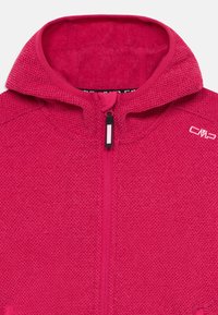 Fleece'owa kurtka z kapturem w intensywnym różowym kolorze, z teksturowaną powierzchnią, pełnym zamkiem błyskawicznym i logo na ramieniu.