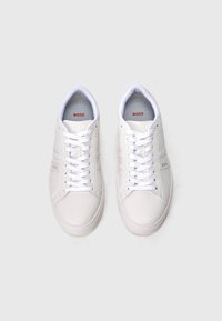 Ζευγάρι λευκά δερμάτινα αθλητικά παπούτσια με την επωνυμία BOSS, με λευκά κορδόνια, σε θέα από πάνω πάνω σε απλό ανοιχτό γκρι φόντο.