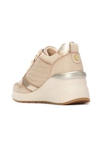 Zapatilla beige con textura acolchada, acentos metálicos y tacón elevado. Presenta cordones planos y detalle de marca en el talón. Suela de goma.