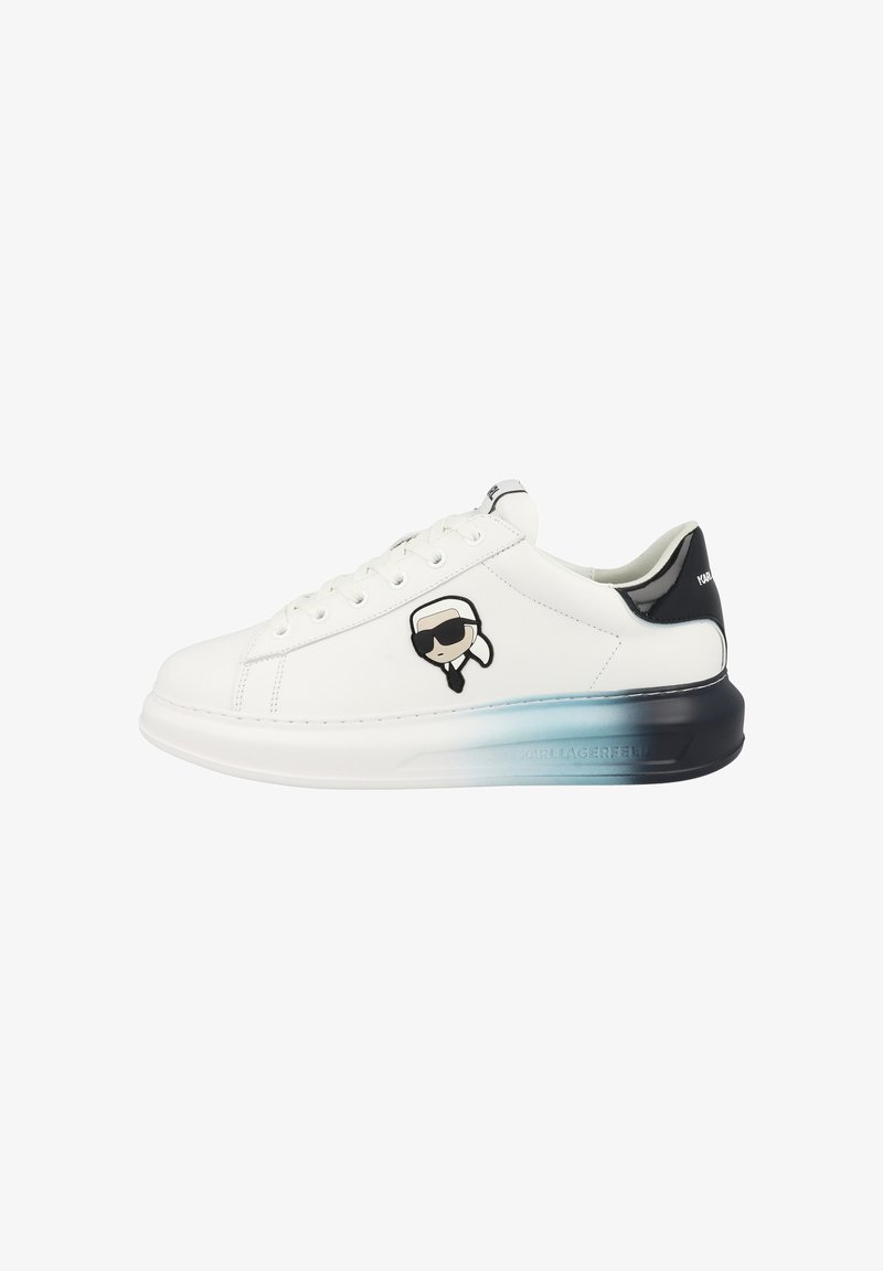 Sneaker bianca bassa con accento nero sul tallone, suola sfumata blu-nera, lacci e faccina da cartone animato con occhiali da sole sul fianco.