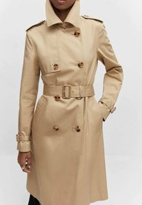 Cappotto trench beige con design doppiopetto, grandi bottoni, vita con cintura e spalline, realizzato in un tessuto morbido.