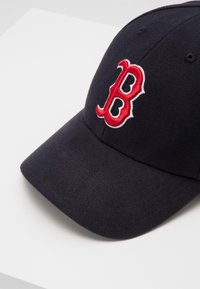 Marineblaue Baseballmütze aus Stoff mit einem gestickten roten "B"-Logo, das in Weiß eingefasst ist. Verfügt über einen gebogenen Schirm und sechs Belüftungslöcher.