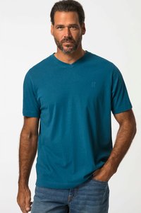 T-shirt en v teal en tissu doux avec des manches courtes, associé à un jean en denim bleu. Branding subtil sur la poitrine.