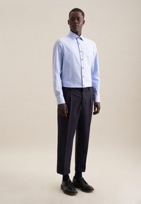 Lichtblauw overhemd met lange mouwen en knoopsluiting, gecombineerd met donkere broek en zwarte schoenen. Glad materiaal, gestructureerd ontwerp, op maat gemaakte pasvorm.