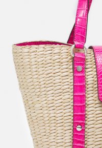Borsa a tracolla in paglia intrecciata con una tracolla e un pattina a motivo coccodrillo di un rosa brillante, caratterizzata da una superficie liscia e dettagli in metallo.