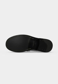 Semelle de chaussure en cuir noir avec coutures visibles et talon lisse, taille 41, présentée sur un fond uni gris clair.