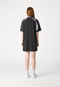 Vestido atlético preto e branco com um corte descontraído, apresentando mangas curtas estampadas e costas lisas, feito de um tecido leve.