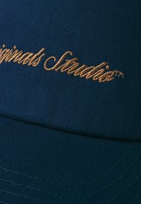 Navy baseball cap with a structured design, featuring gold embroidered text. Text is prominently displayed on the front panel.