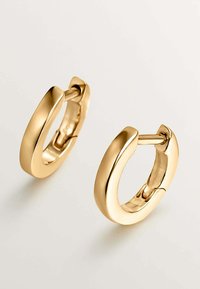 Pendientes de aro dorados que presentan una superficie lisa y pulida con un diseño sin costuras y un cierre de bisagra. Forma redonda y gruesa con un acabado brillante.