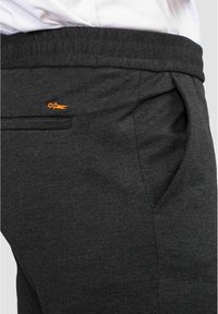 Mörkgrå, texturerade joggingsbyxor med sidofickor och en orange broderad logga. Har en mjuk midja för ökad komfort.