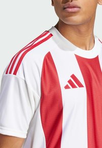Rood en wit gestreepte sporttrui met een ronde hals, voorzien van drie rode schouderstrepen en een zwart Adidas-logo op de linkerkant van de borst.