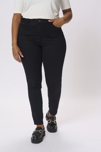 Jeans neri a vita alta con taglio slim, realizzati in denim elasticizzato; presentano una chiusura con bottone frontale e tasche laterali. Abbinati a mocassini neri.