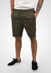 Olivgröna shorts i bomull, med resårmidja och dragsko, sidofickor och rak passform i knä längd.