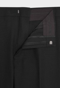 Czarne spodnie wykonane z gładkiego materiału, z zamkiem błyskawicznym i dyskretnym metalowym akcentem. Wnętrze ma wzmocnione szwy i czyste linie.